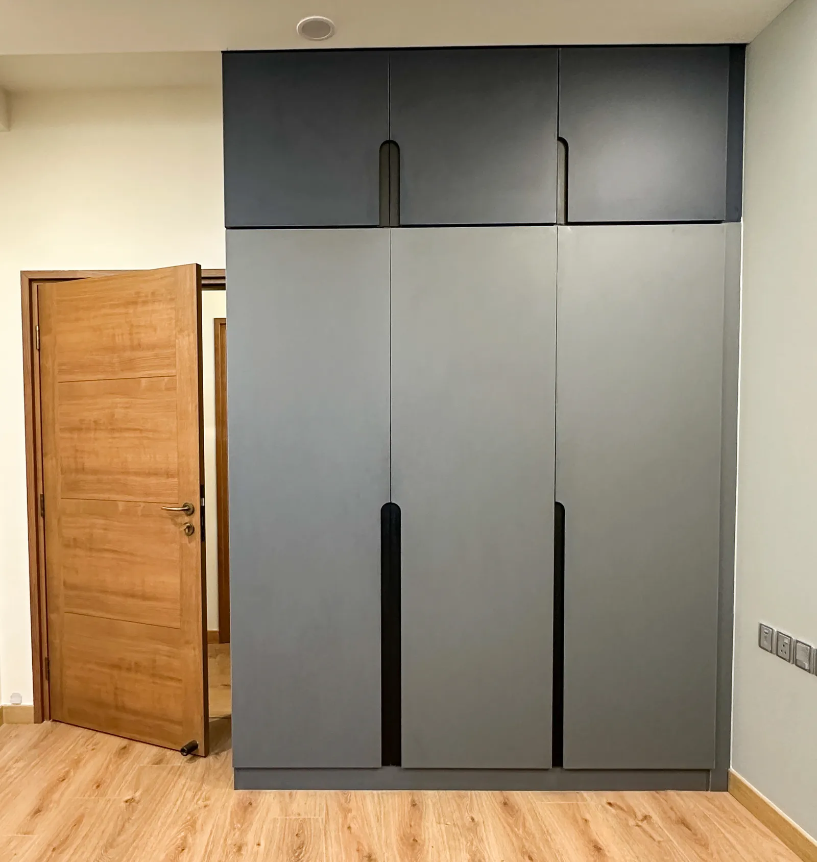 Grey handleless wardrobe with black recessed handles — Somani's Residence